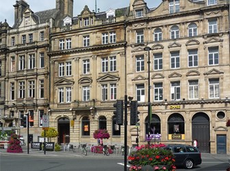 General view of a street scene featuring a row of terraced listed buildings in Newcastle, UK.