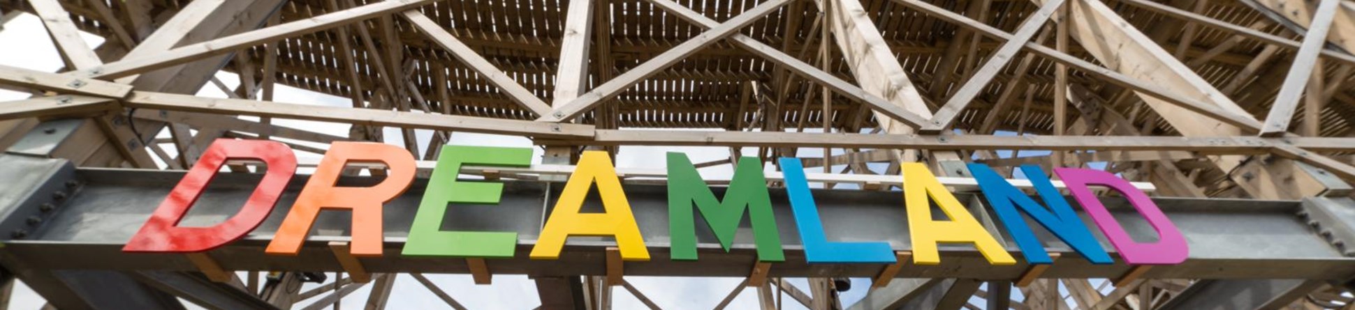 The sign above the entrance to Dreamland in Margate. Each letter in the banner is a different colour. In the background is the structure of the rollercoaster.