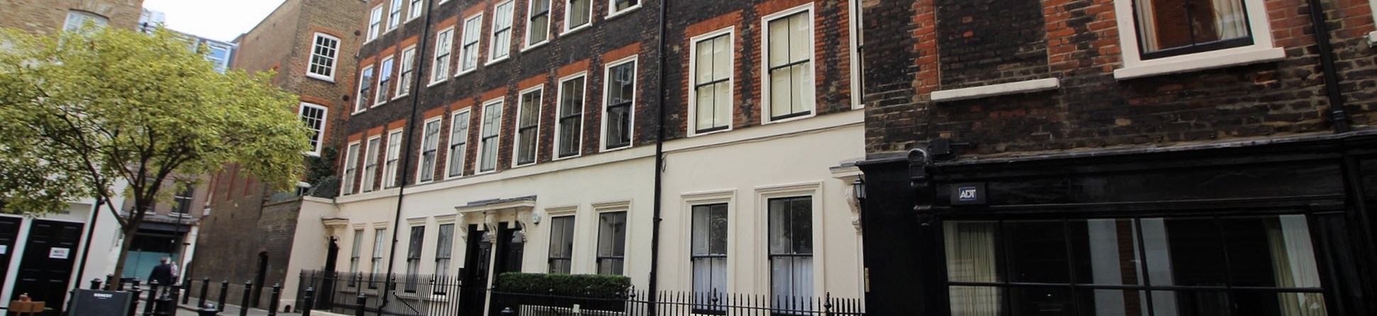 View of Georgian buildings with railings and bollards in front of them.