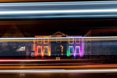 Night image of a building lit up in rainbow colours