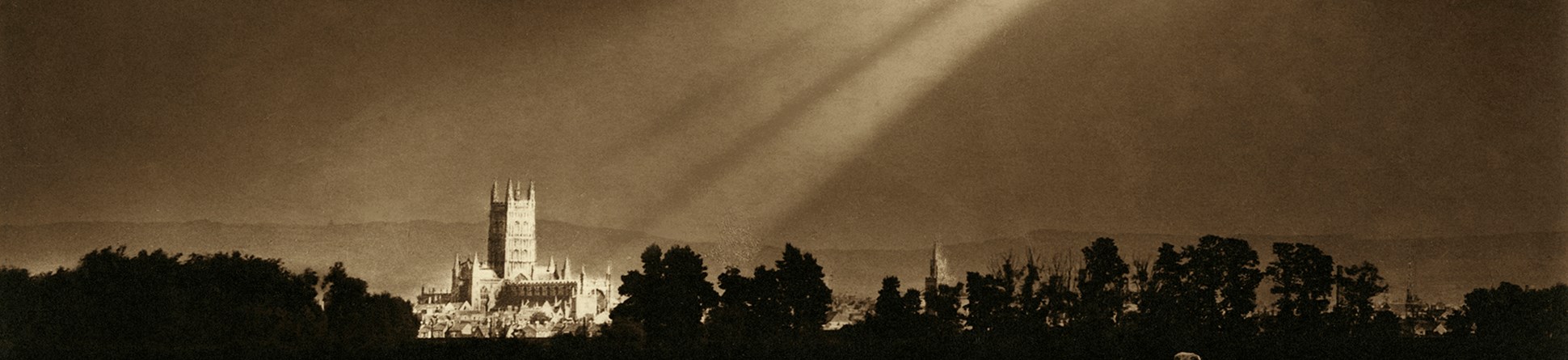 Archive photo of sunlight breaking through clouds and lighting Gloucester cathedral.