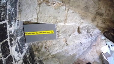 A worn stone spiral staircase with warning sign on one step.