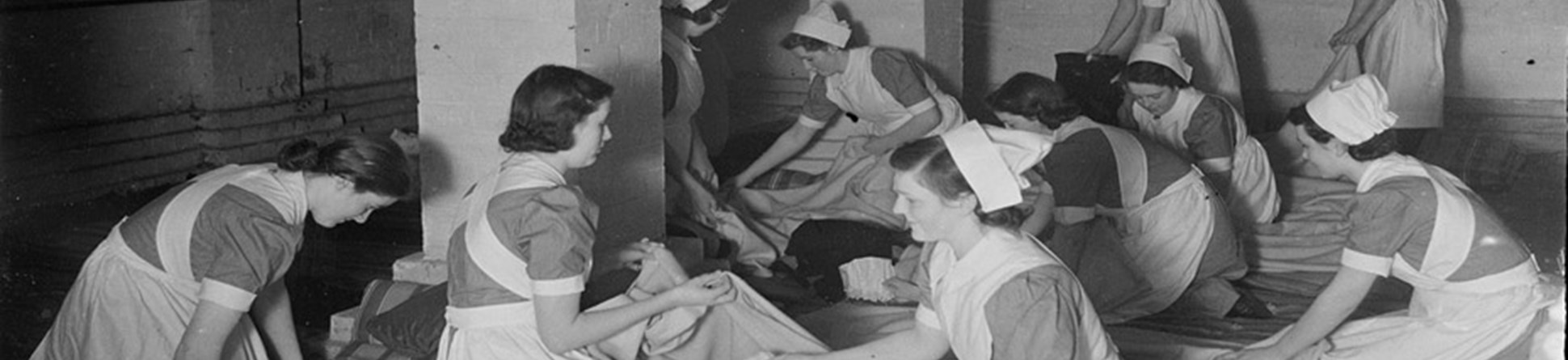 Nurses preparing bedding on the floor of an underground air raid shelter at Manchester Royal Infirmary