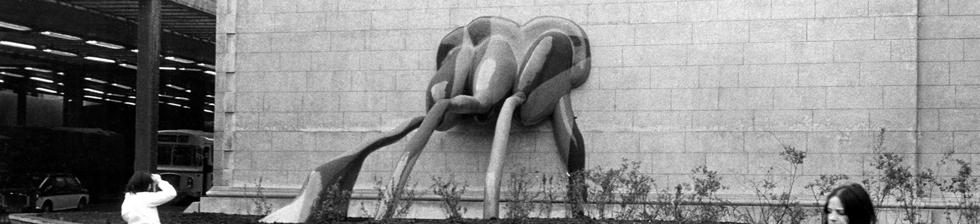 Fibreglass sculpture spilling out from an external wall into a flower-bed